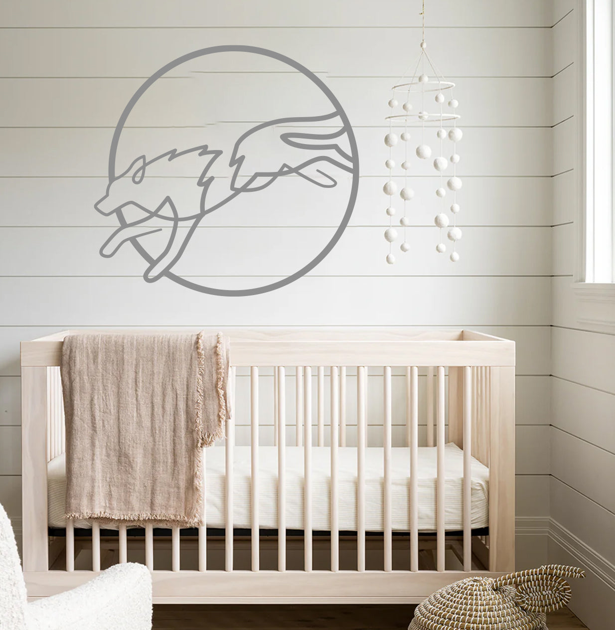 a baby's room with a crib and a wall decal of a